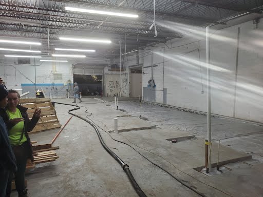 A group of people are standing in an empty warehouse.