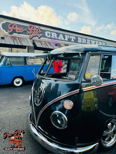 A black vw bus is parked in front of a building.