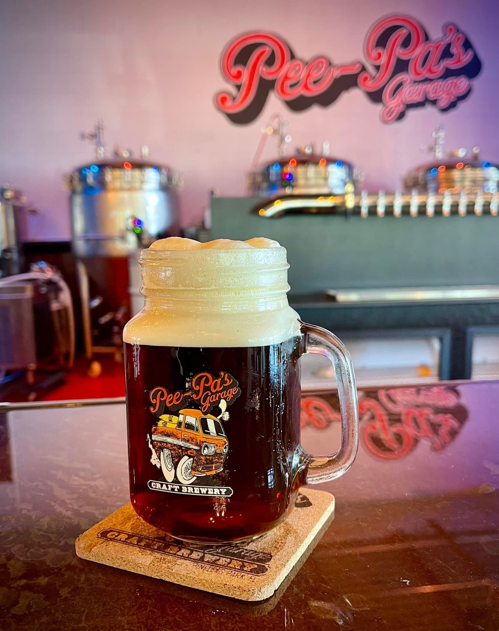 A mug of beer is sitting on a coaster on a bar.