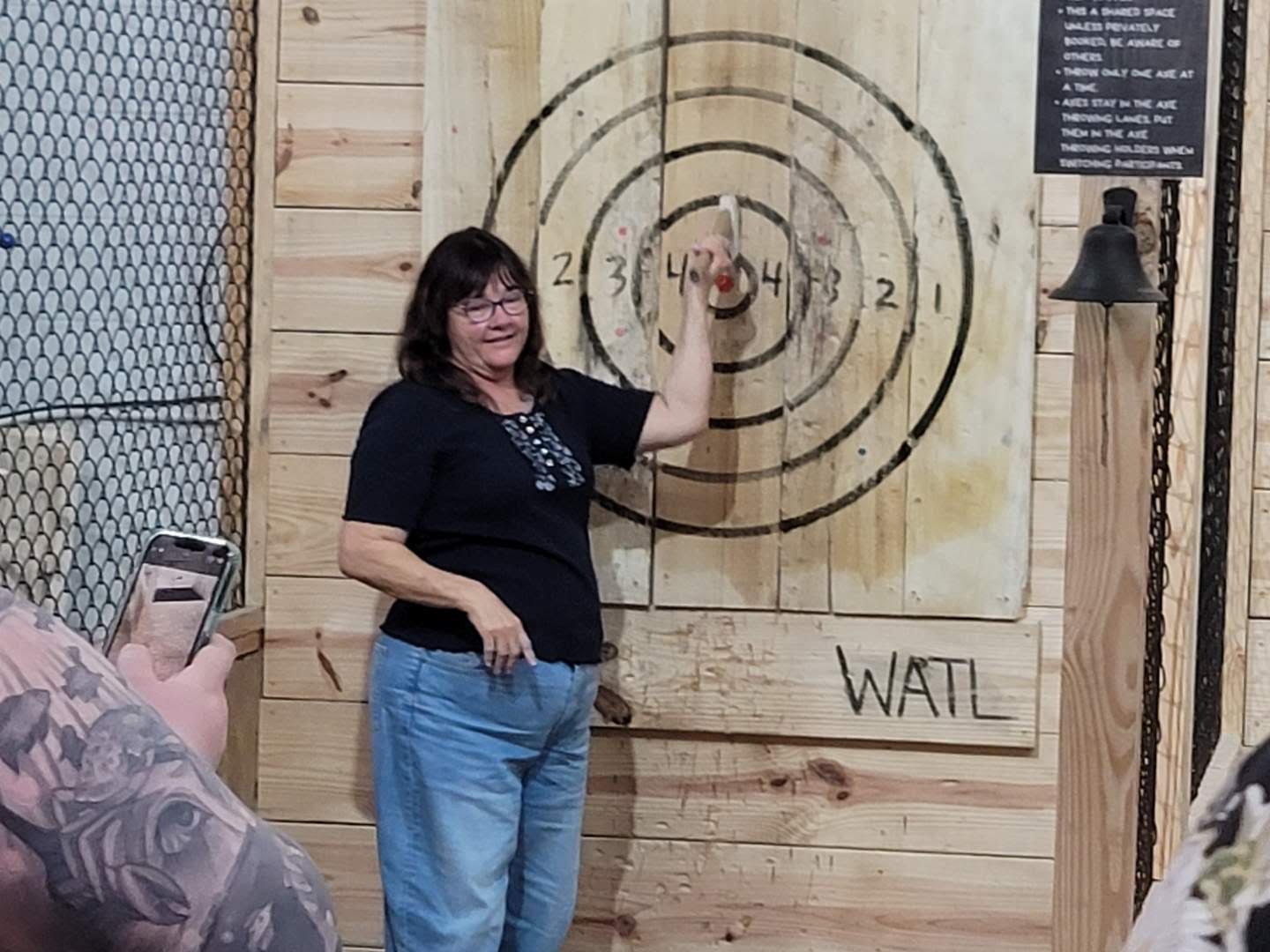 A woman is standing in front of a wooden target.