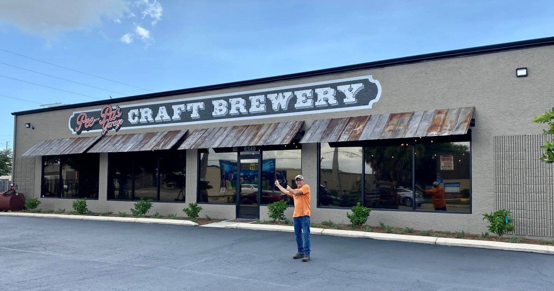 A man is standing in front of a building that says craft brewery.