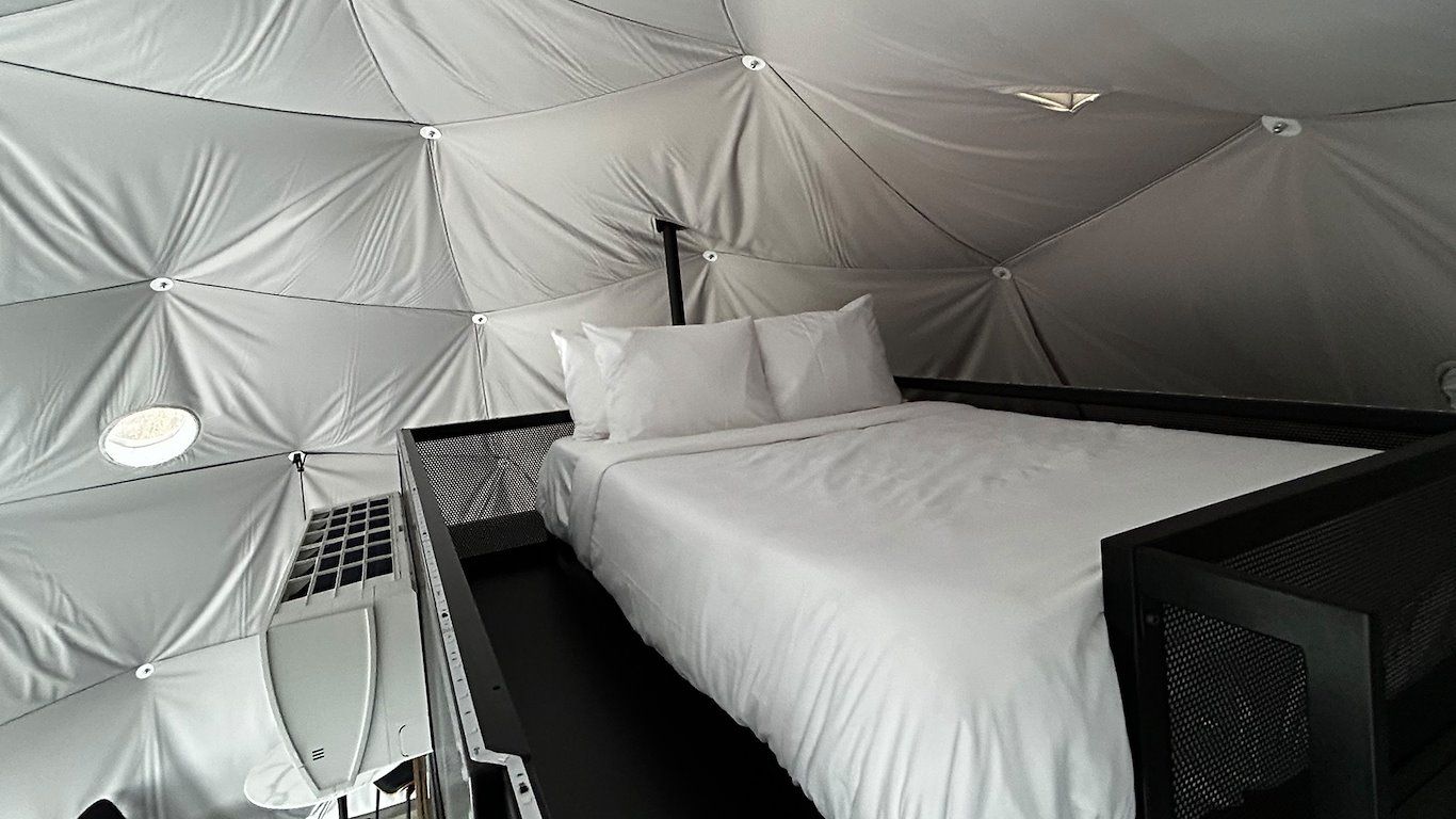 Interior of a white geodesic dome with a bed and black accents.