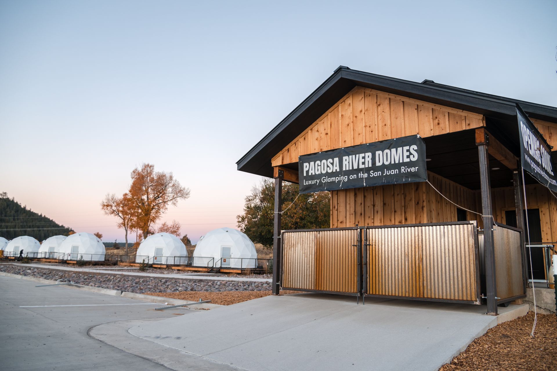 Entrance to Ponderosa River Domes lodging. Wooden building with sign; white domes in background.