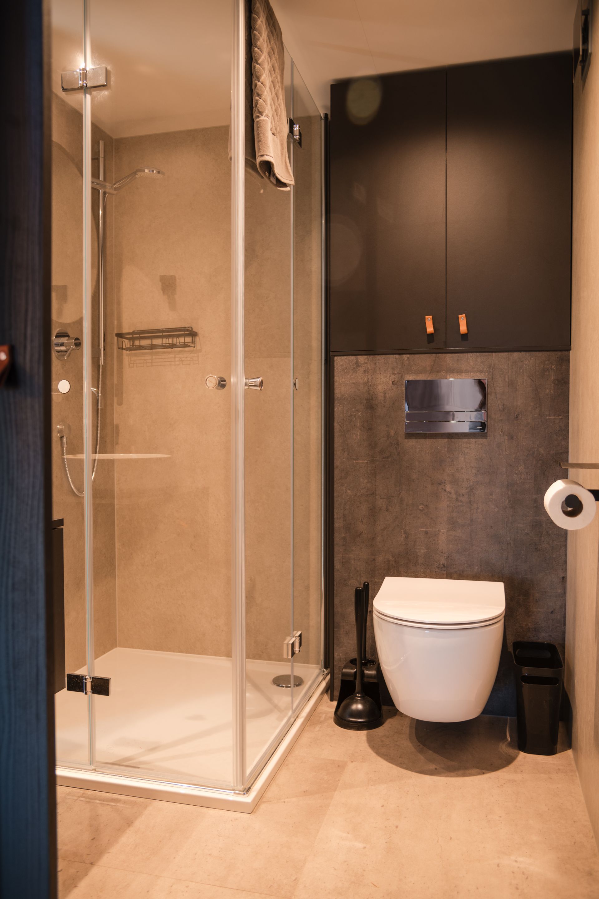 Modern bathroom with a shower, toilet, and dark cabinets.