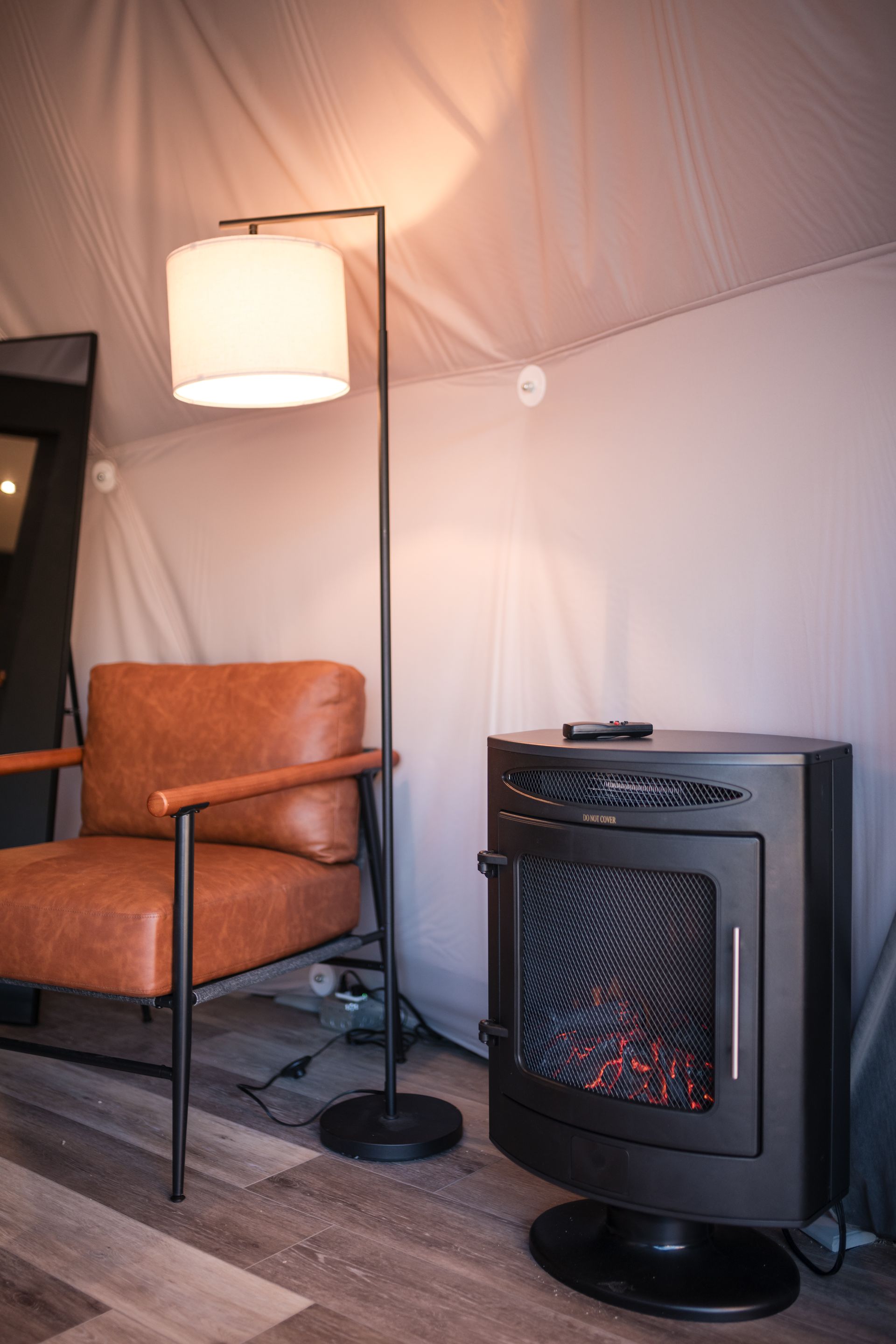 Cozy interior with a leather armchair, floor lamp, and a black electric fireplace.