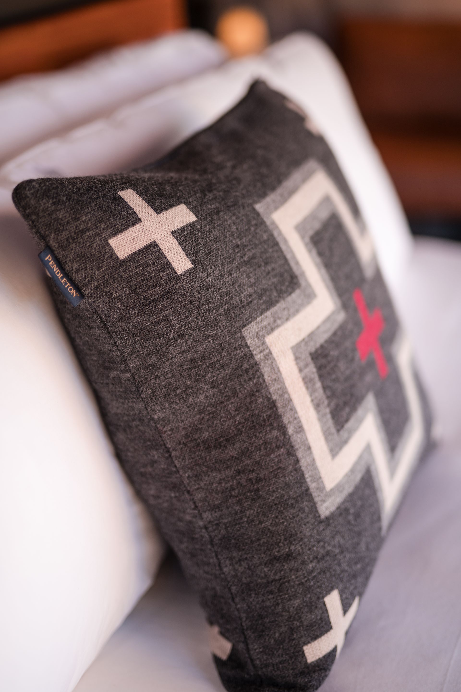 Gray throw pillow with geometric design, resting on white pillows.