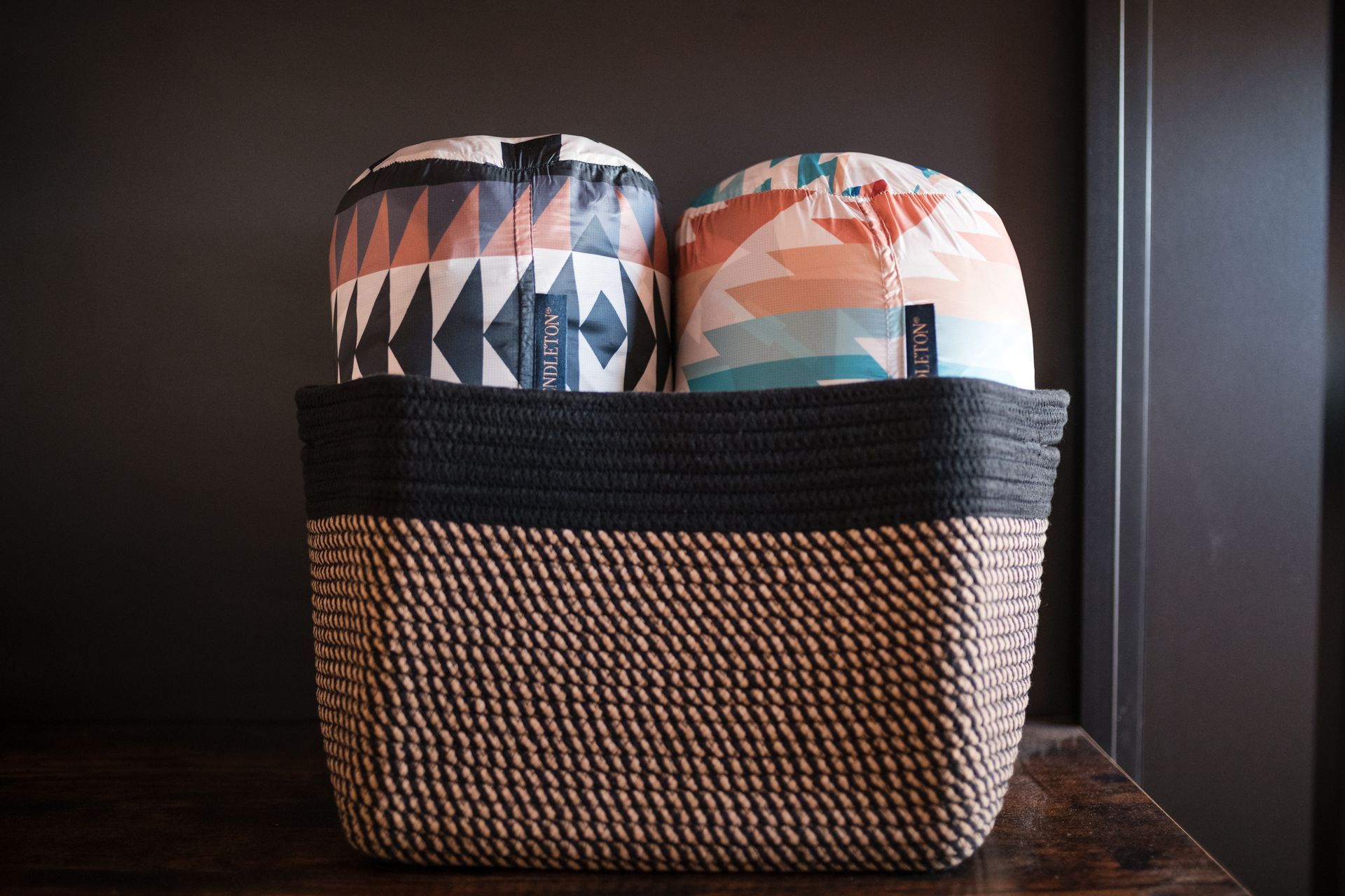Basket with two patterned pillows, dark background.