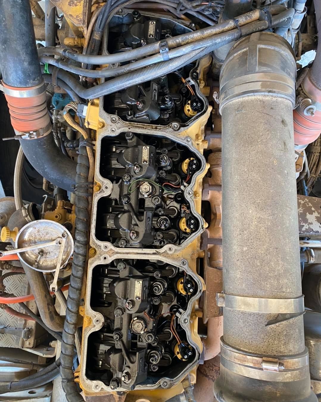 Top-down view of an engine, revealing rocker arms, valve stems, and oil. The engine is surrounded by hoses and tubes — Traction Diesel Services in Clermont, QLD