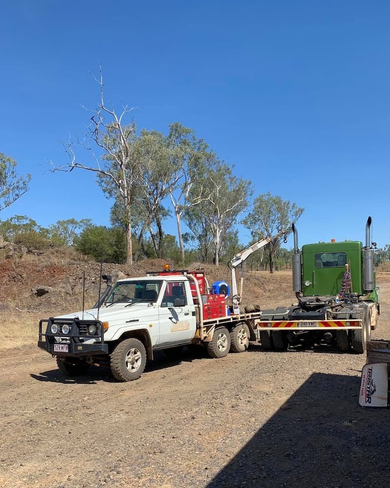 White Truck Towing a Green Semi-truck on a Dirt Road Under a Blue Sky — Traction Diesel Services in Clermont, QLD