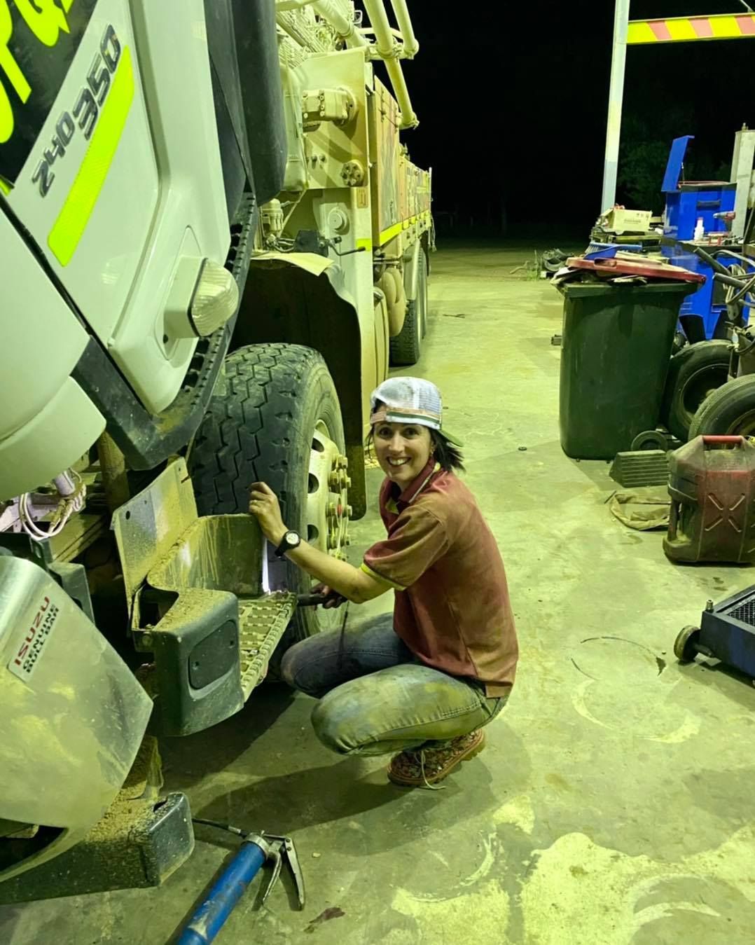 A Person Crouches, Inspecting a Truck Tire at Night — Traction Diesel Services in Clermont, QLD