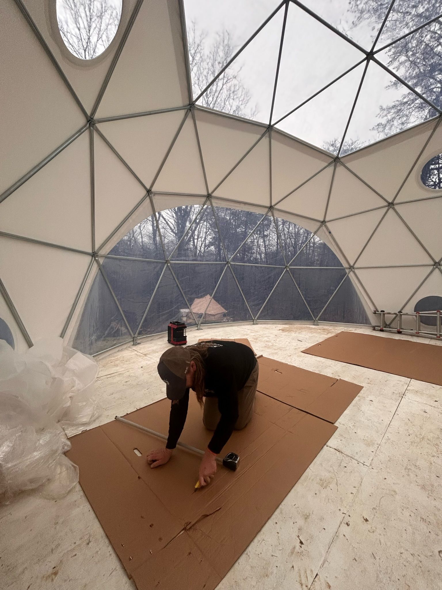 A man is measuring a piece of cardboard in a dome