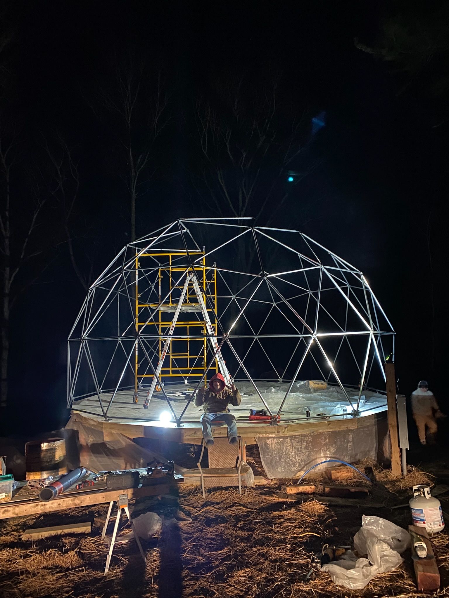A dome is being built at night in the woods.