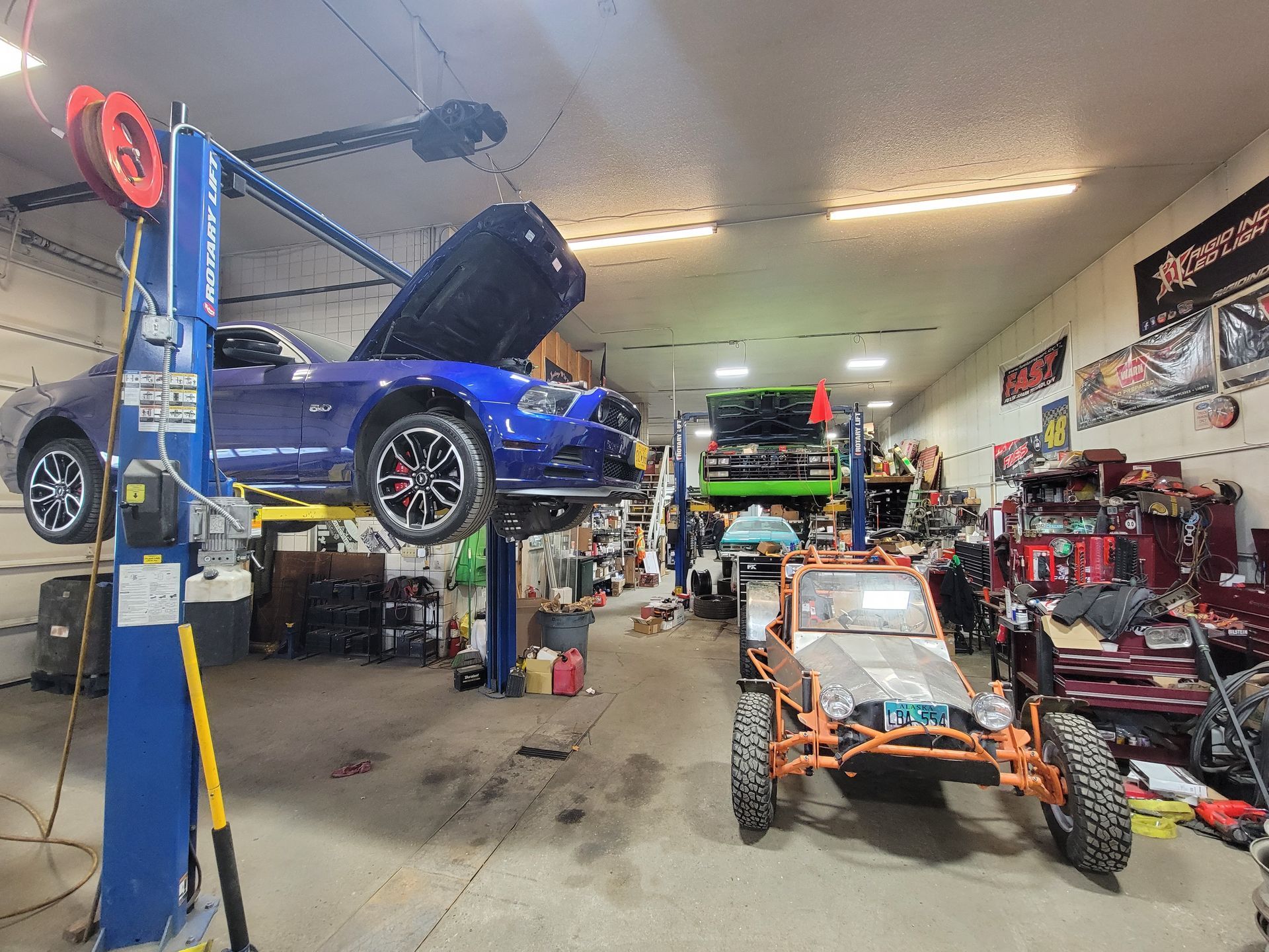 A blue car is on a lift in a garage.