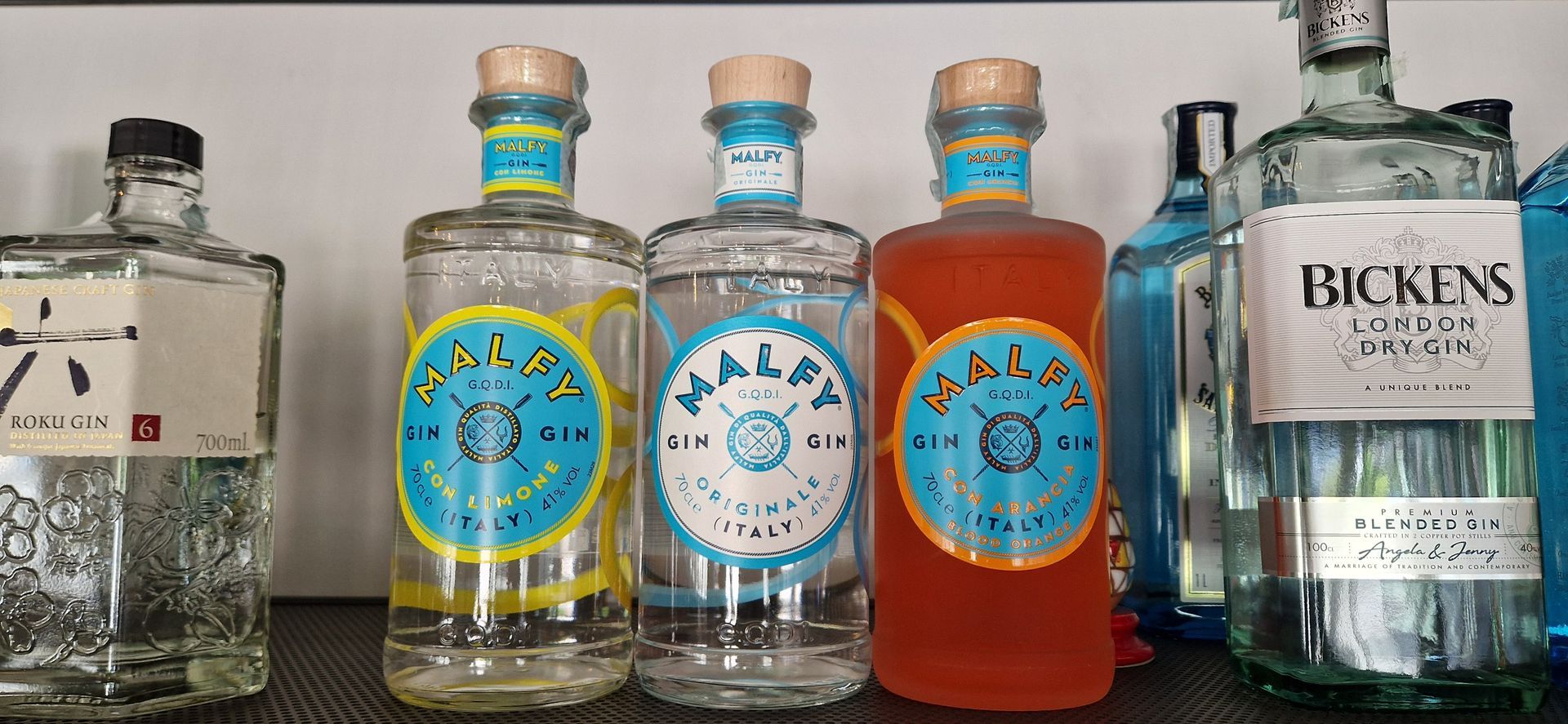 Una fila di bottiglie di alcolici sono allineate su uno scaffale.