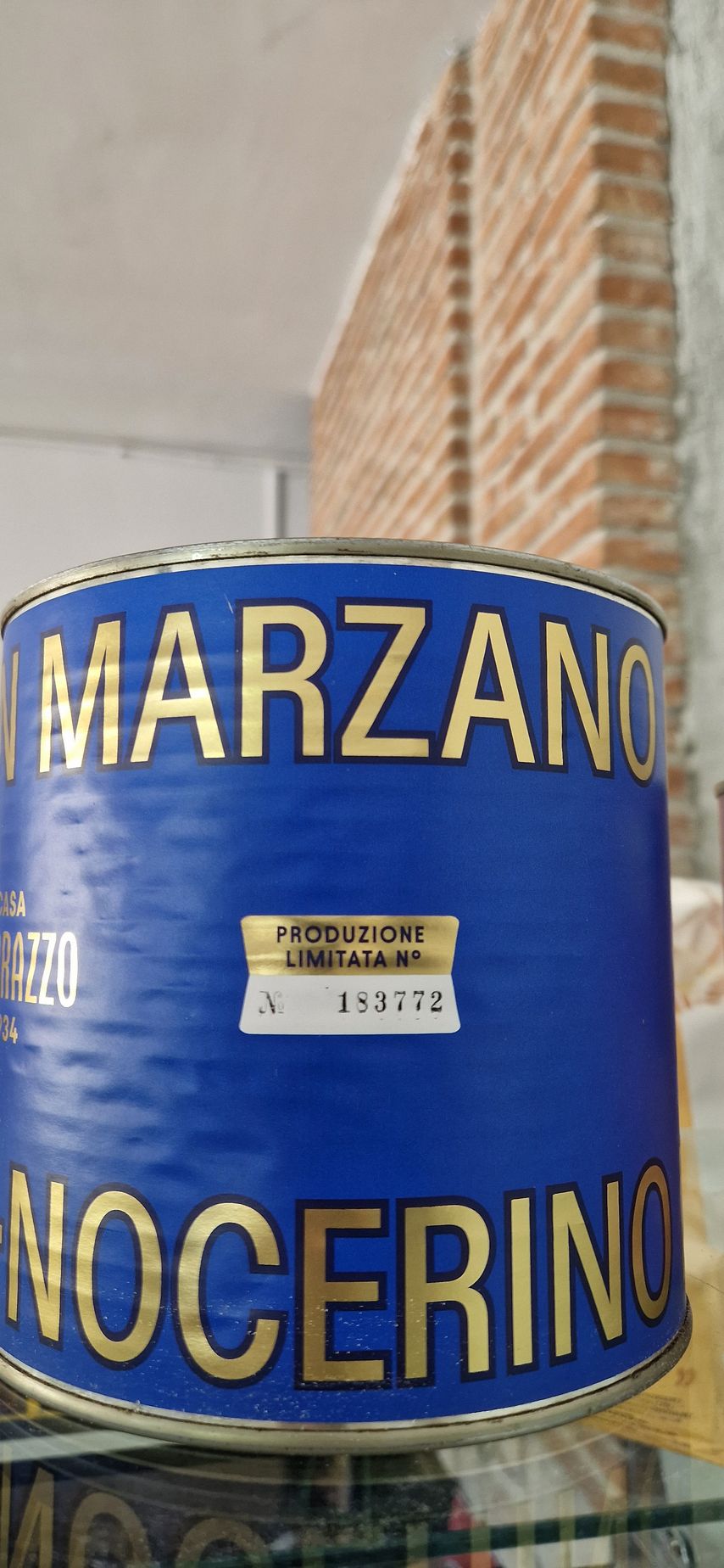 Una lattina blu di Marzano Nocerino è appoggiata su uno scaffale di vetro.