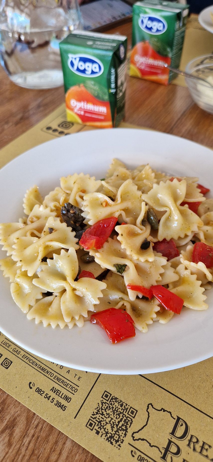 Un piatto bianco con pasta e verdure su un tavolo.