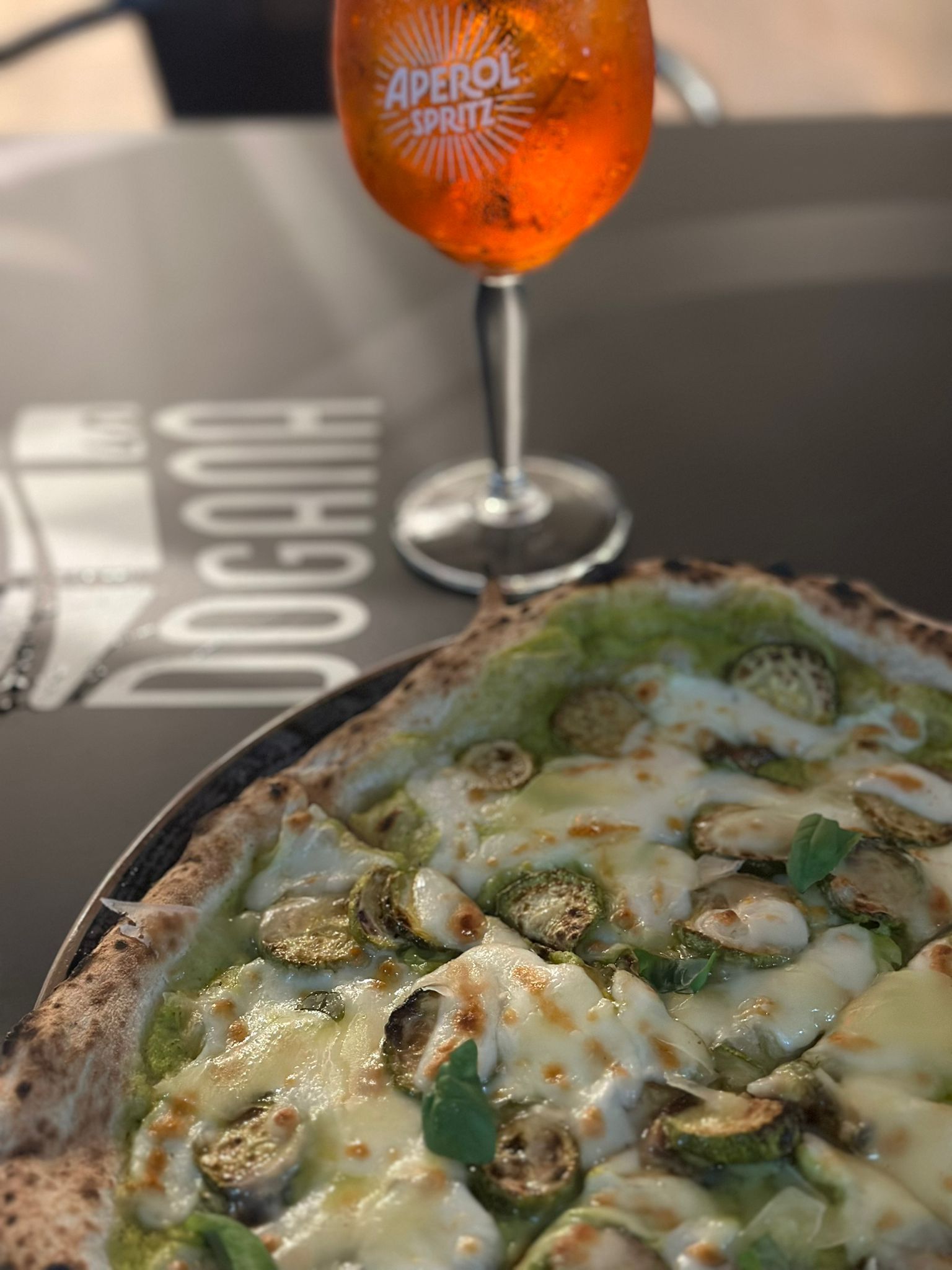 Una pizza e un bicchiere di aperol spritz sono su un tavolo.