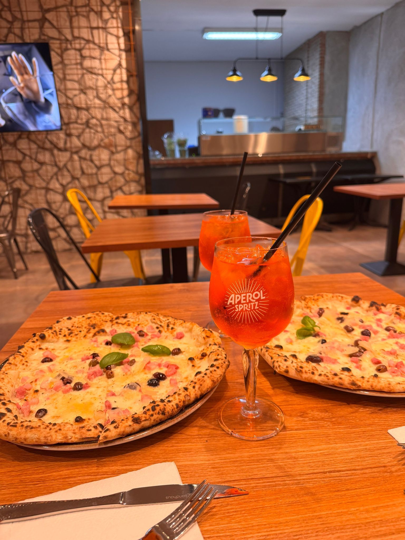 Due pizze e una bibita su un tavolo di legno in un ristorante.