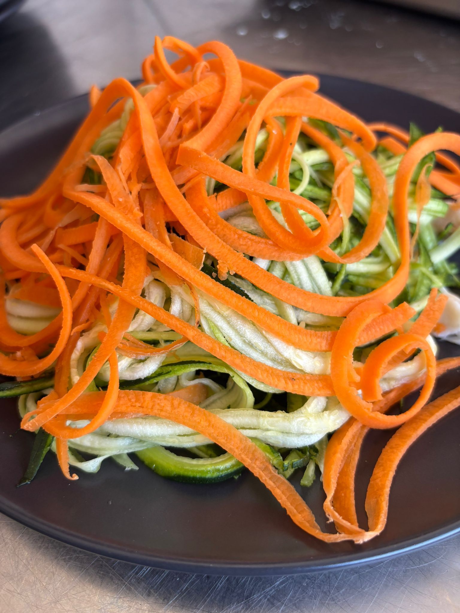 Un piatto di carote e zucchine tagliate a cubetti su un tavolo.