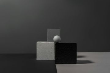 A ball is sitting on top of a black and white cube.
