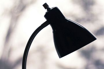 A black lamp is sitting on a table in front of a window