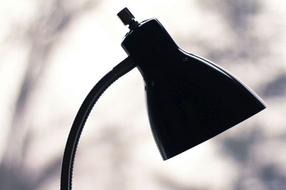 A black lamp is sitting on a table in front of a window
