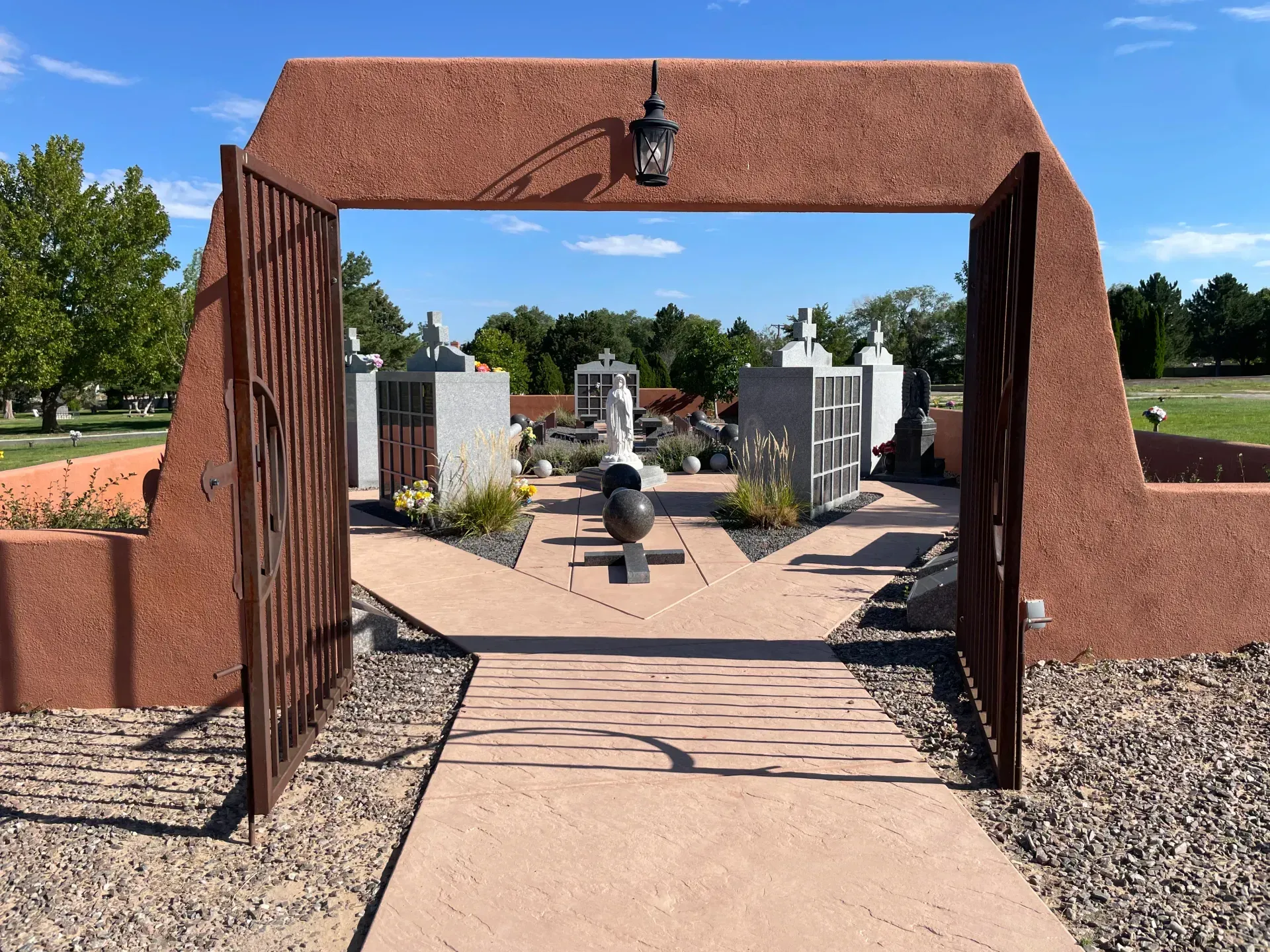 Rendering of a memorial with a central cross and surrounding structures, trees, and sky.