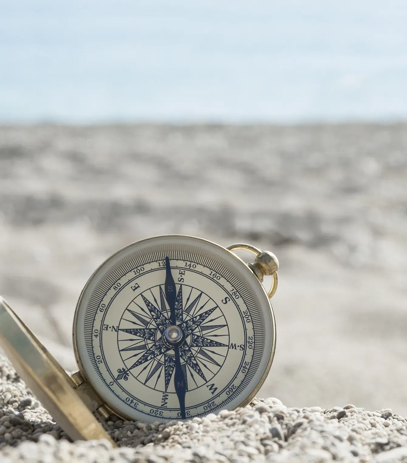 Una brújula está en la arena de una playa.