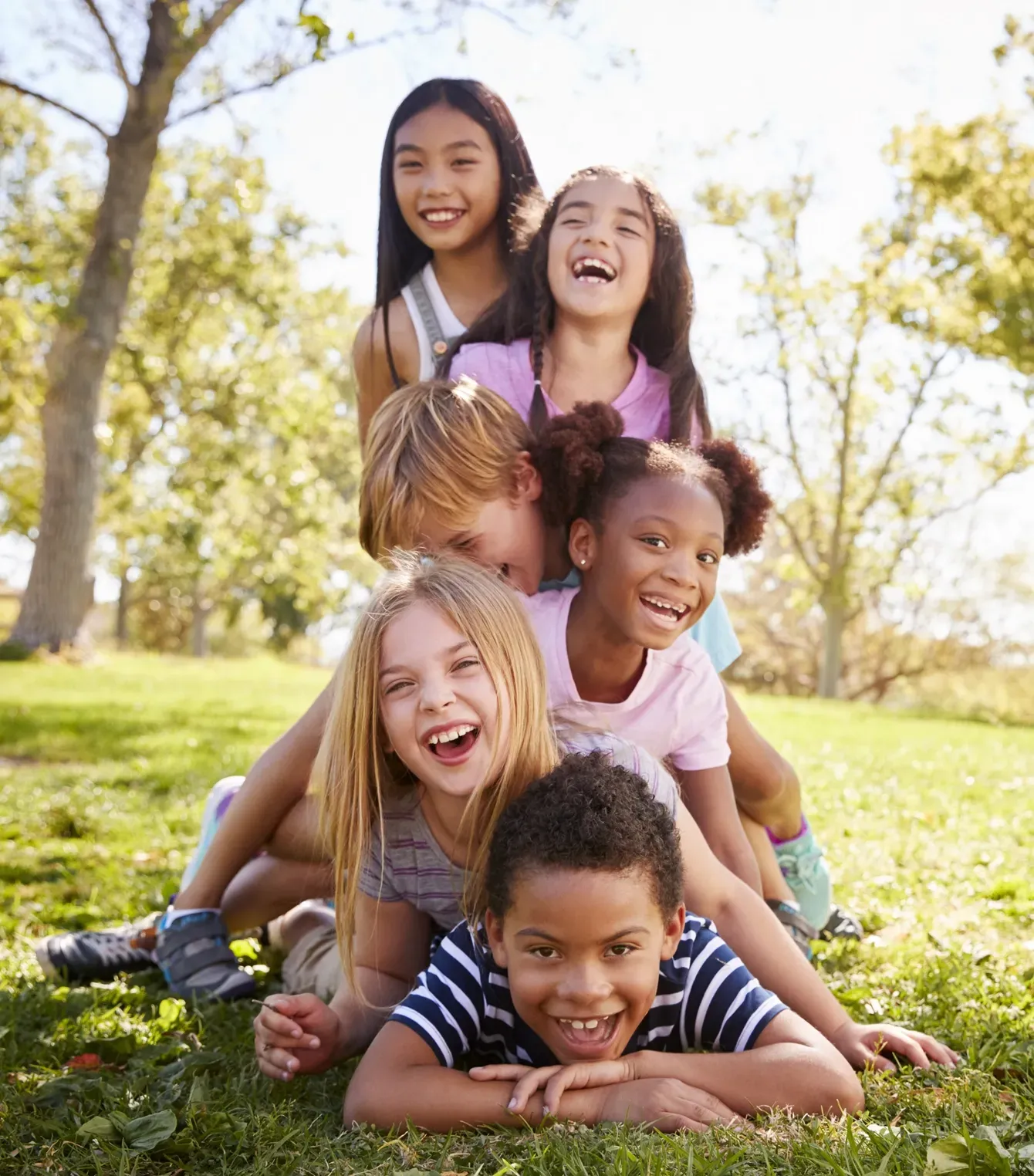Un grupo de niños están acostados uno encima del otro en el césped.