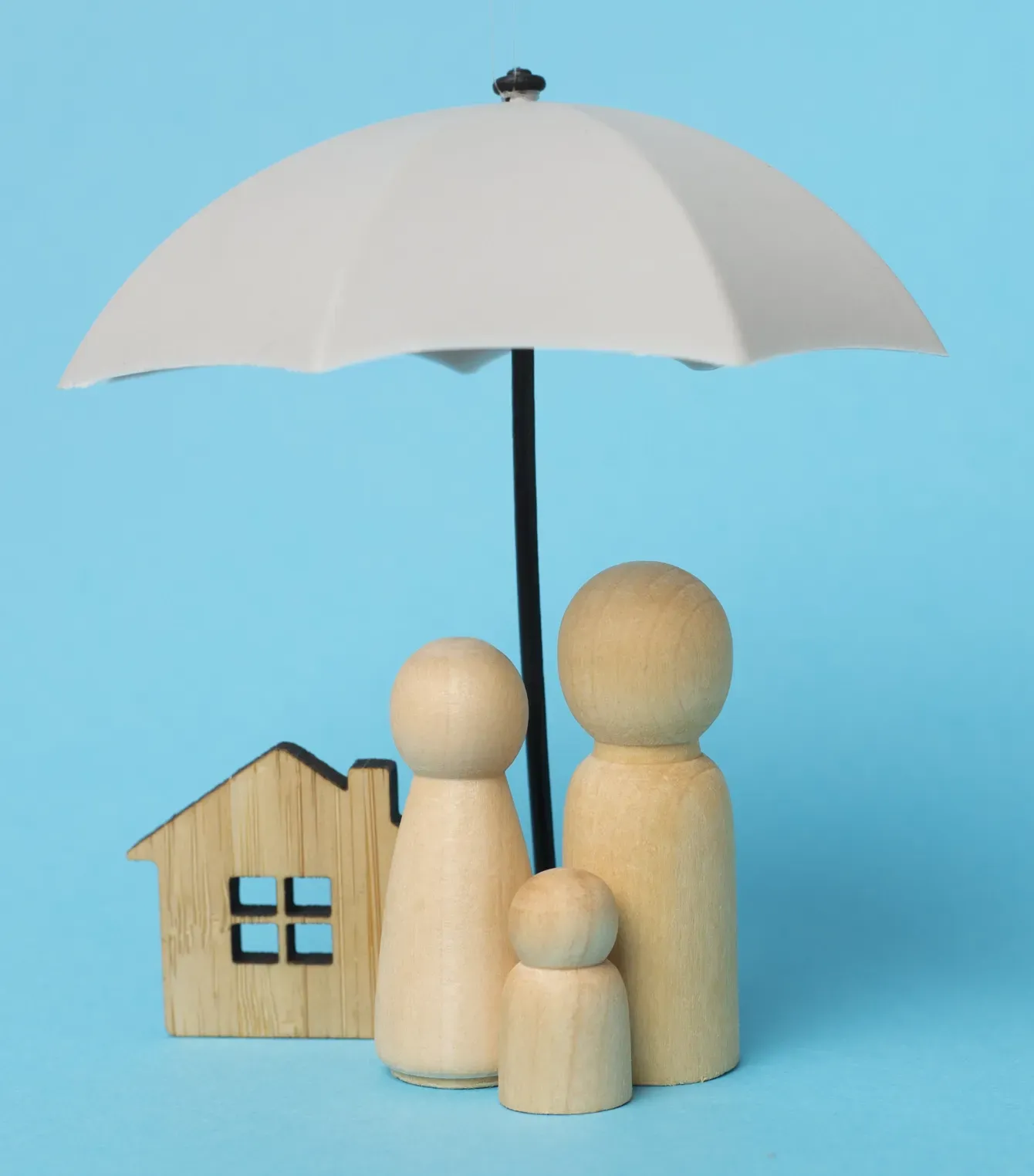 Una familia de madera está bajo una sombrilla al lado de una casa de madera.