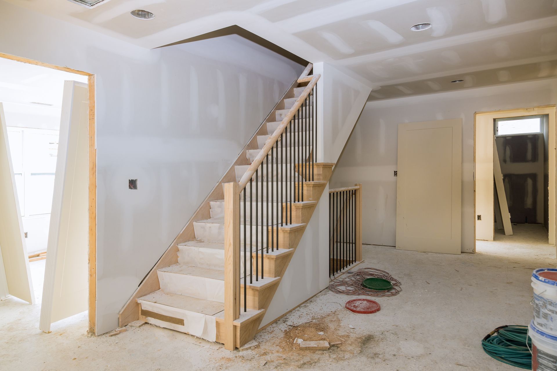 Interior under construction with stairs, drywall, and partially completed railing.