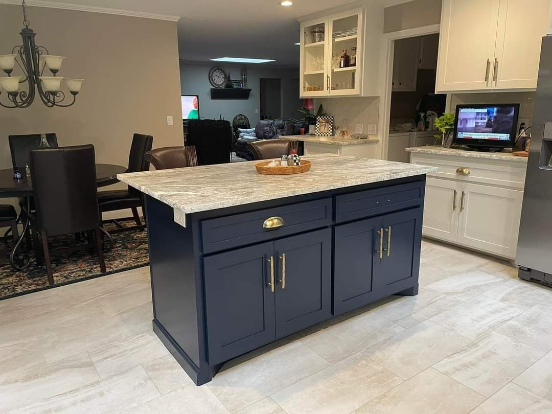 Navy blue kitchen island with light countertop, gold hardware, in a kitchen.