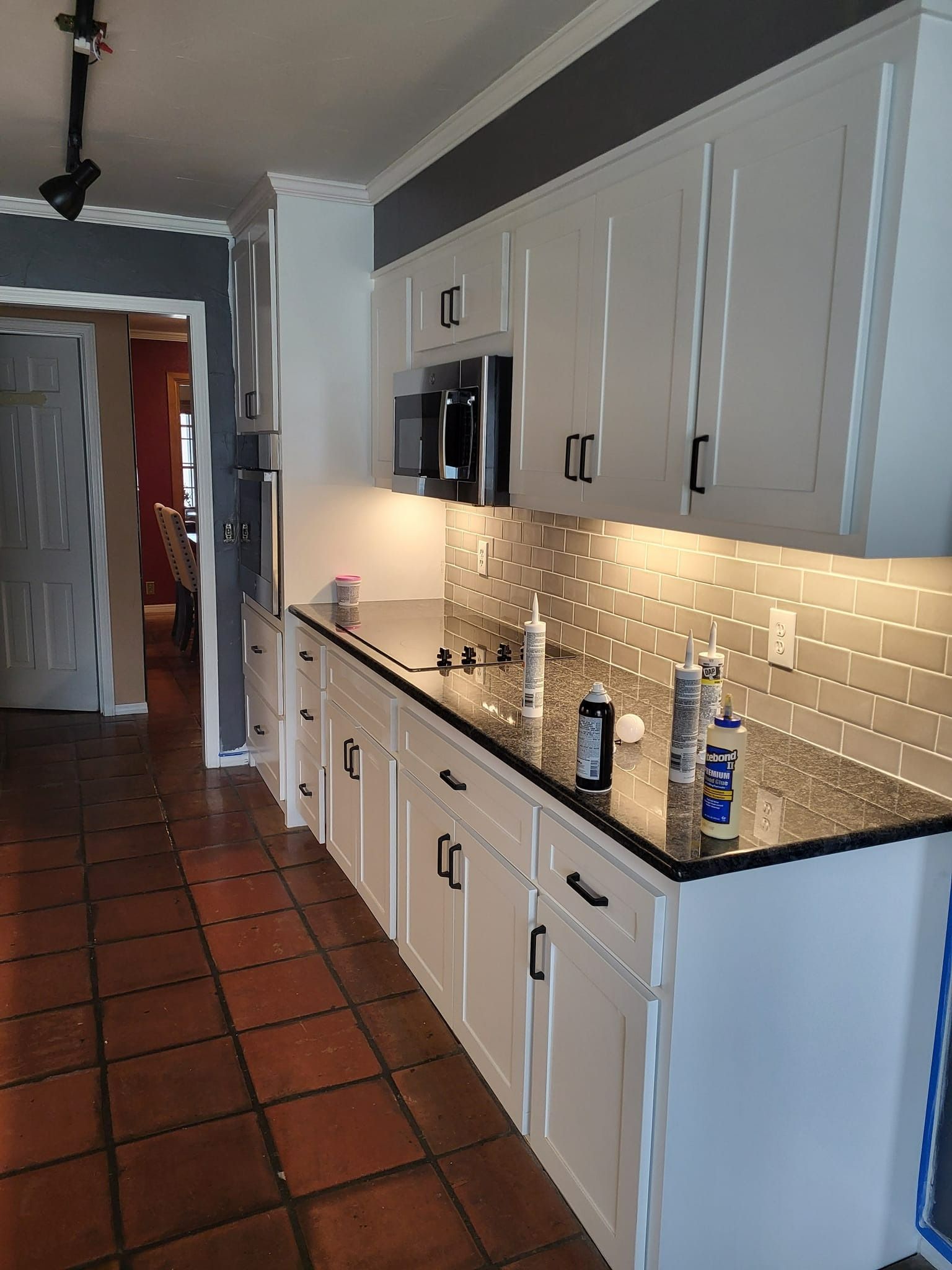 White kitchen cabinets with black countertops and black hardware.