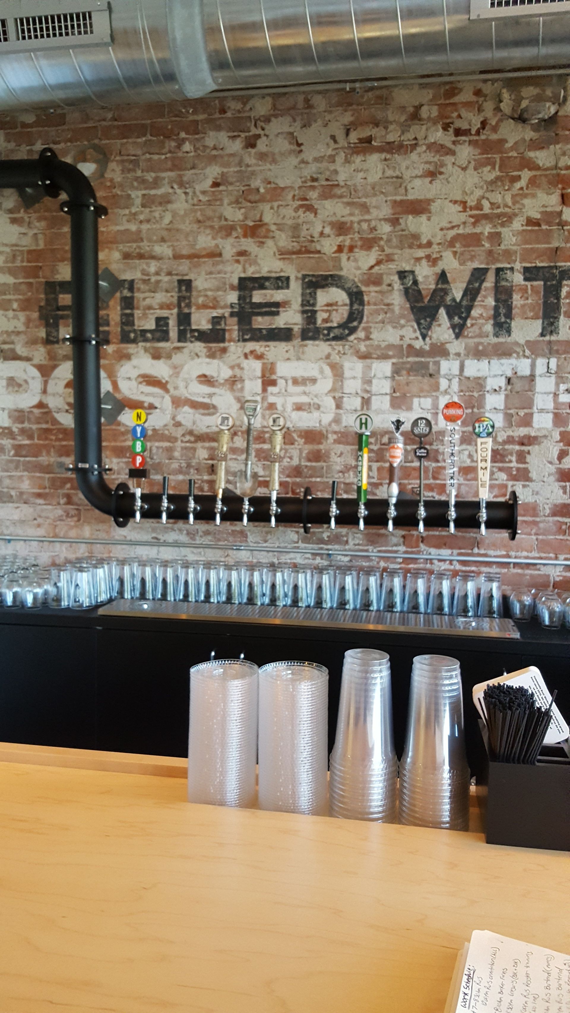 a bar with serveral different draft systems and a brick wall that says filled with possibilities