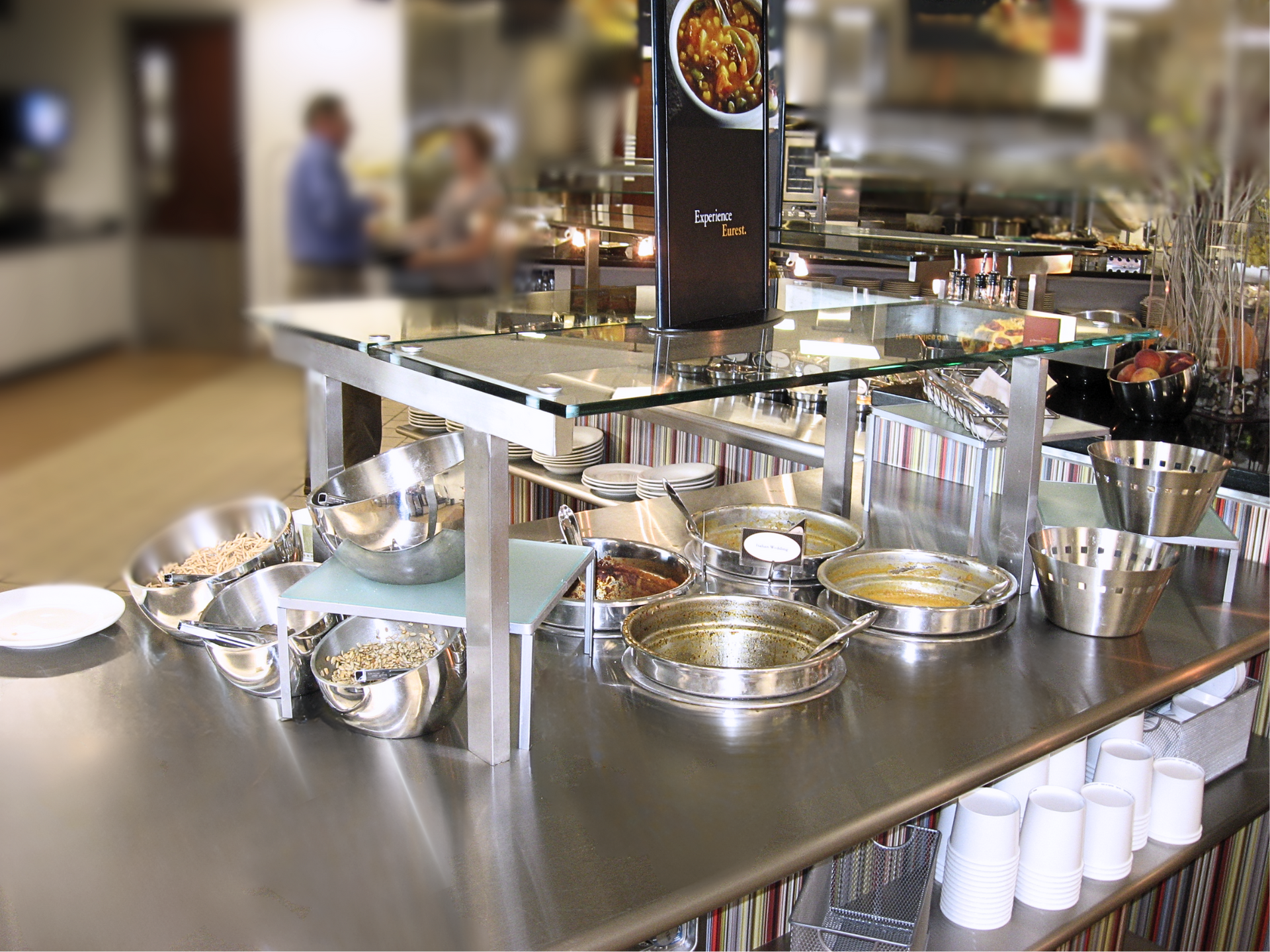 A buffet table with bowls of food and cups on it