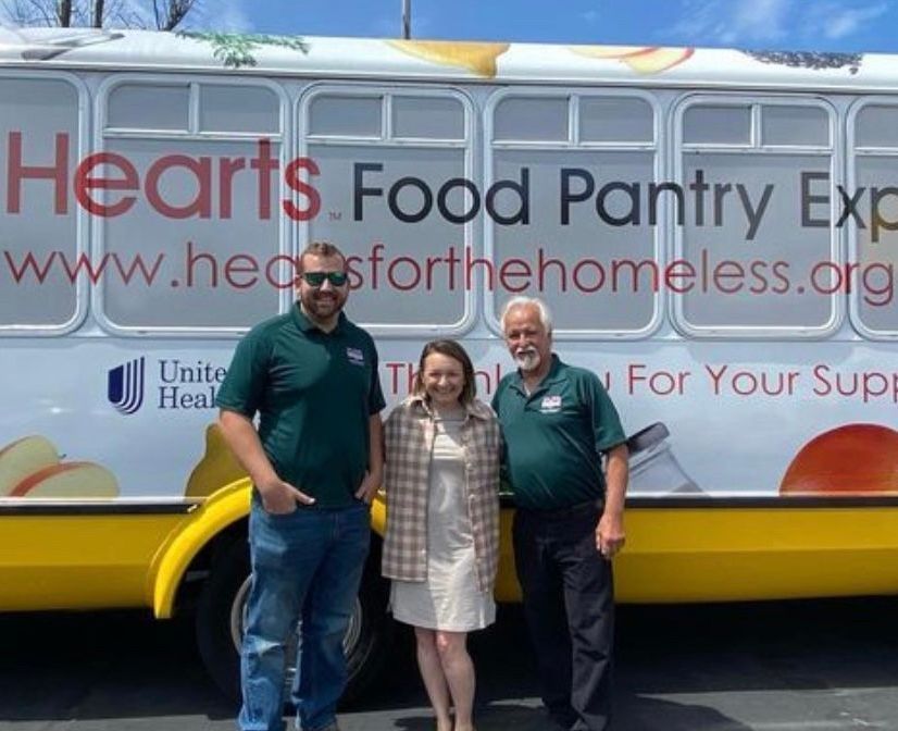 three people stand in front of a hearts food pantry