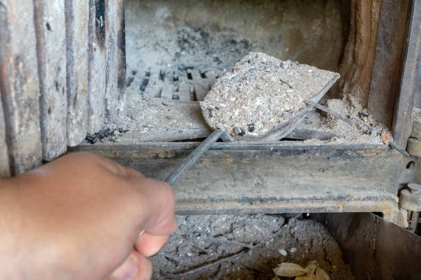 A person is cleaning a fireplace with a shovel.