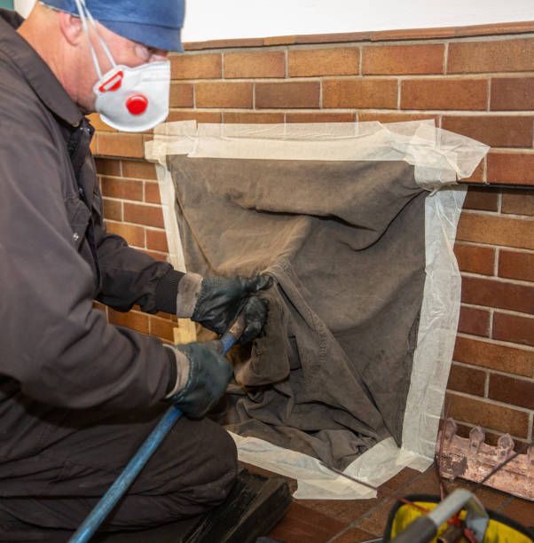 A man wearing a mask is working on a fireplace
