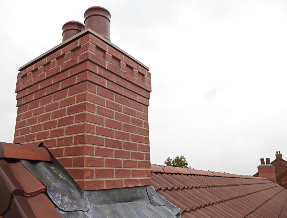 A brick chimney on top of a tiled roof
