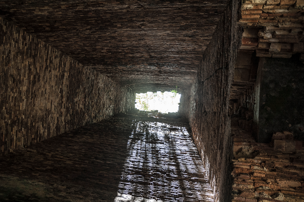 A dark brick tunnel with a window in the middle.