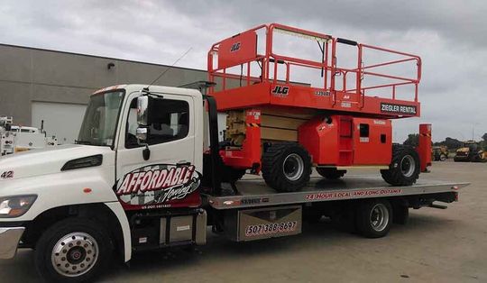 Hydraulic lift being transported on a flatbed — Construction Equipment Transport in Mankato, MN