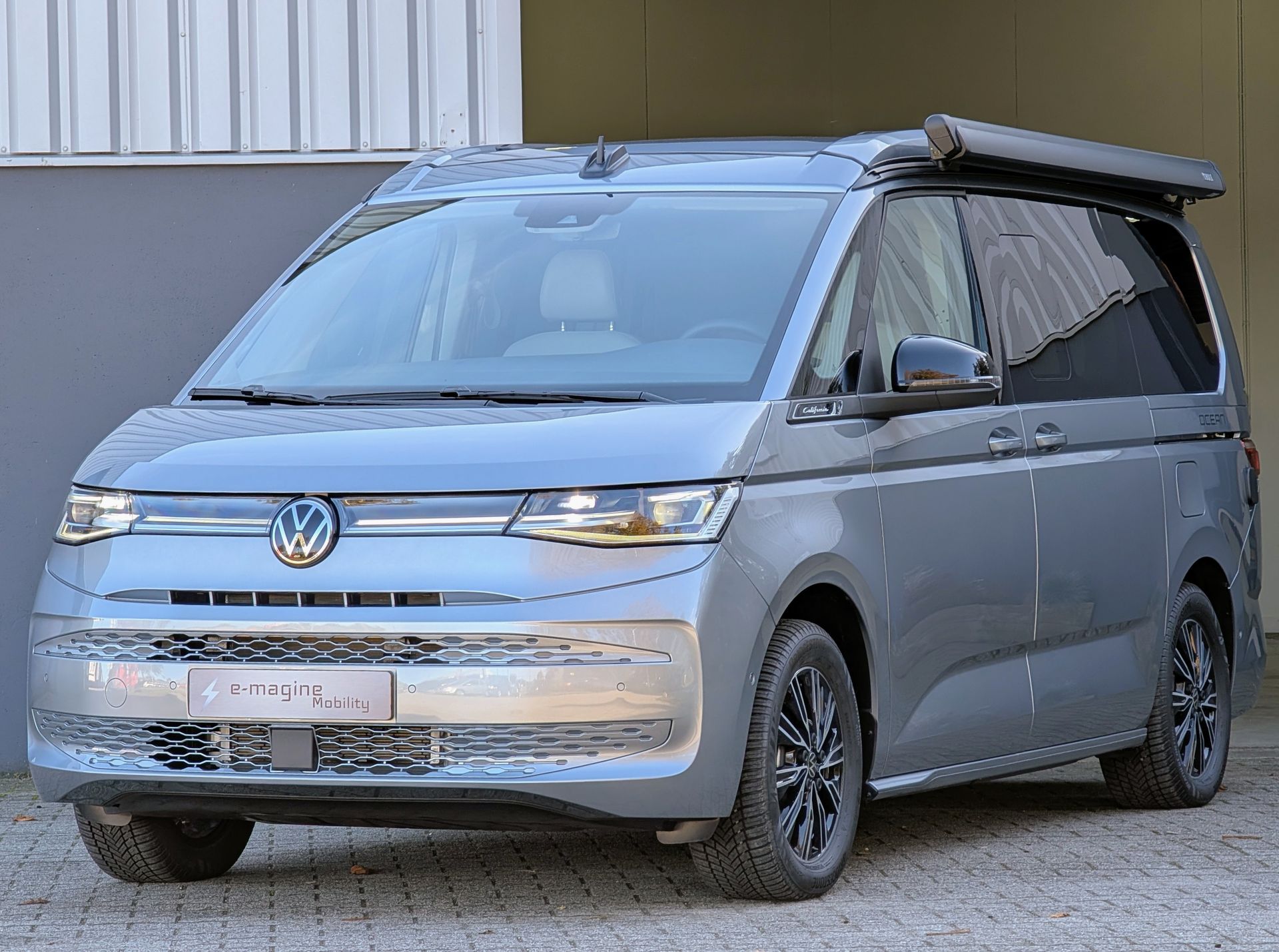 Volkswagen California Ocean eHybrid Mono Silver met hefdak omhoog voor het gebouw van e-magine Mobility in Emmen
