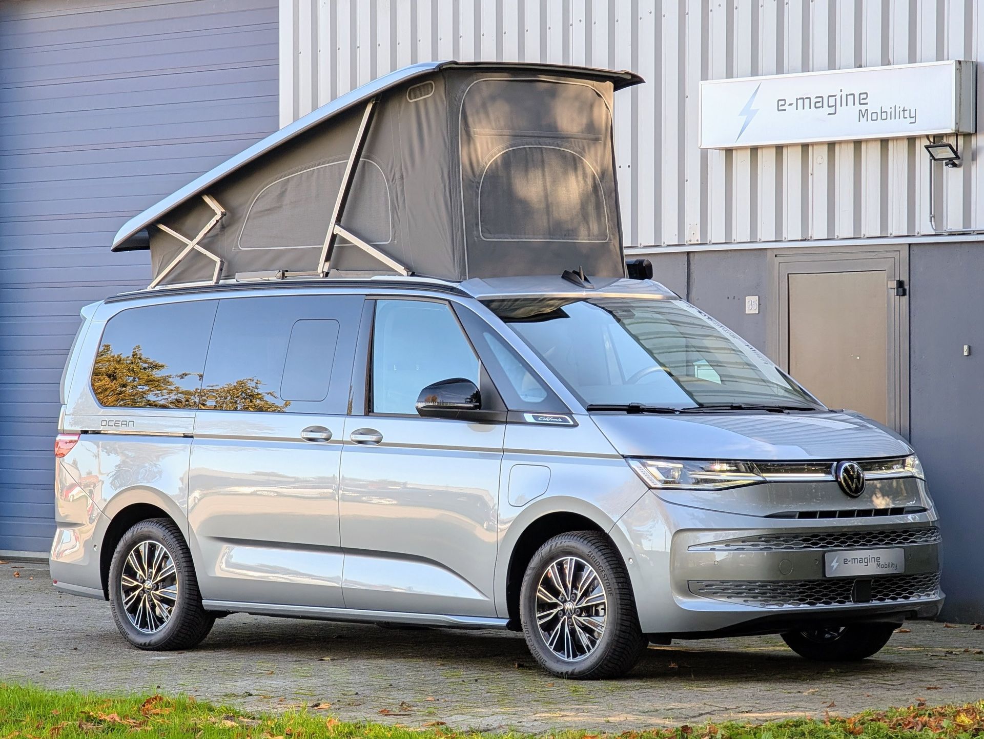 Volkswagen California Ocean eHybrid Mono Silver met hefdak omhoog voor het gebouw van e-magine Mobility in Emmen