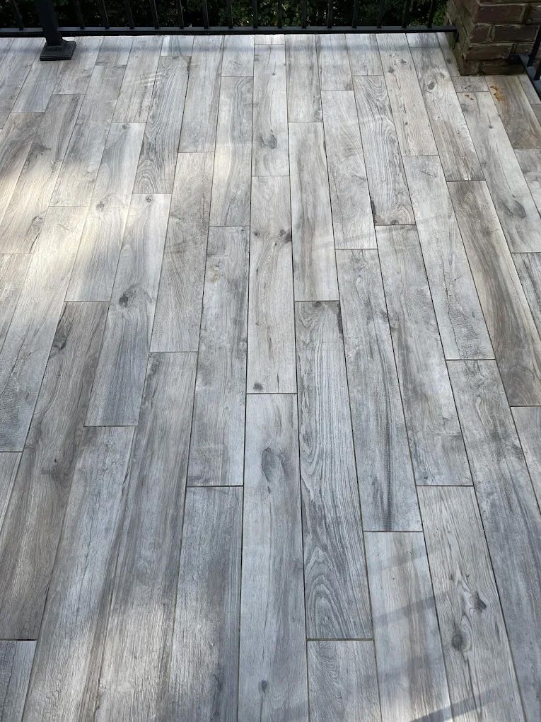 Gray wood-look flooring on a deck, with cracks and uneven surfaces.