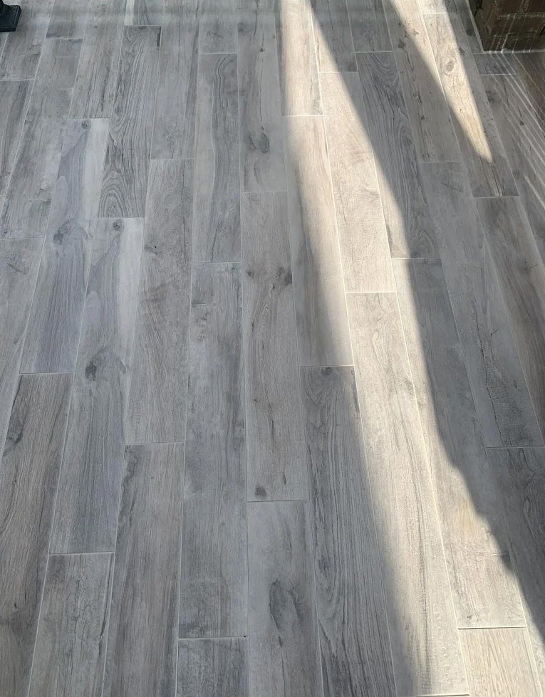 Gray wood-look tile floor with sunlight and shadow.