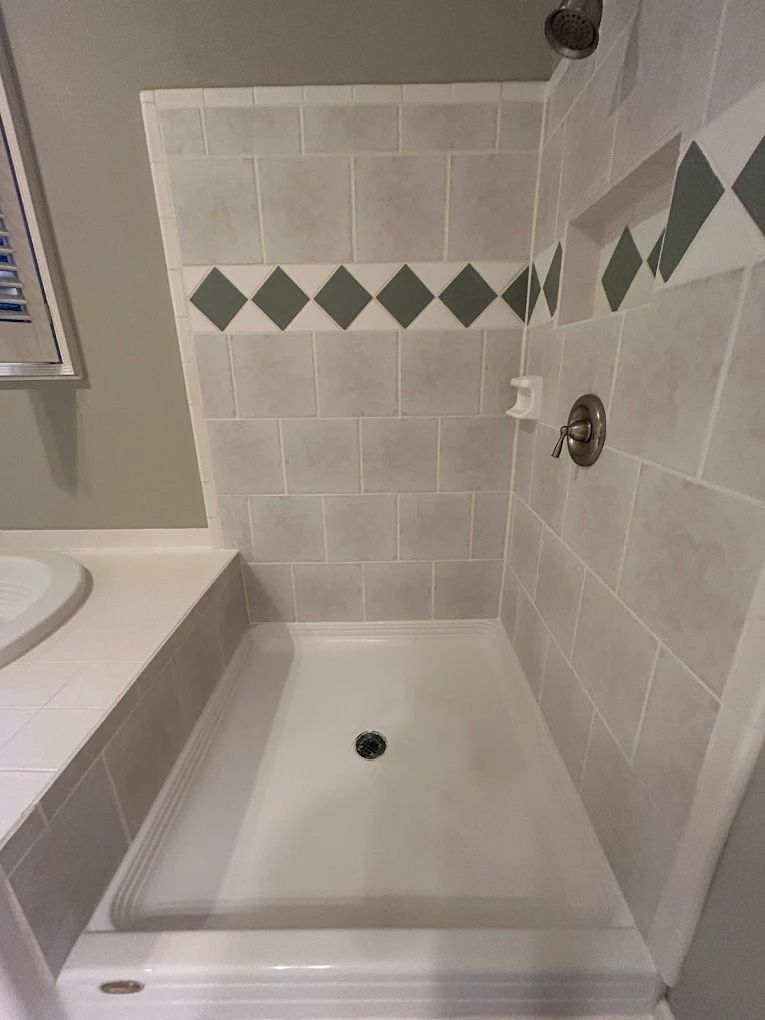 Shower with light gray tiles, diamond-patterned accent tiles, and a white shower pan.