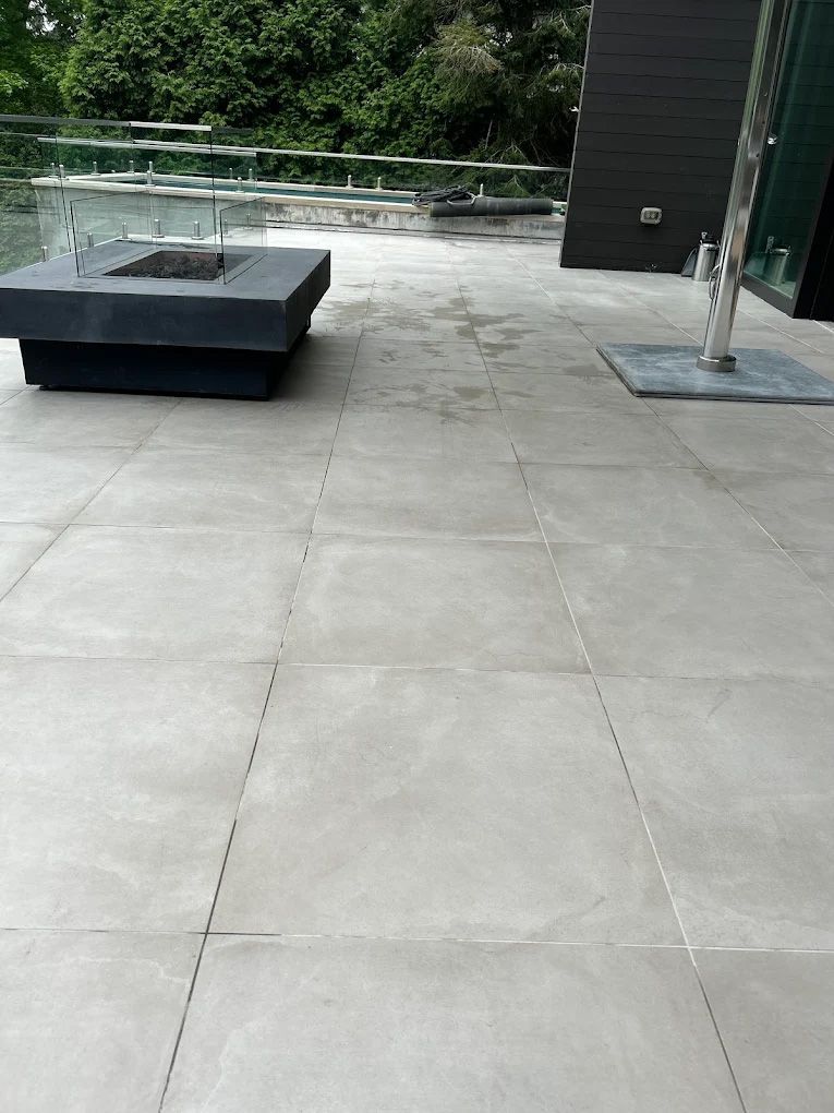 Outdoor patio with gray tiles, a fire pit, and glass railing.