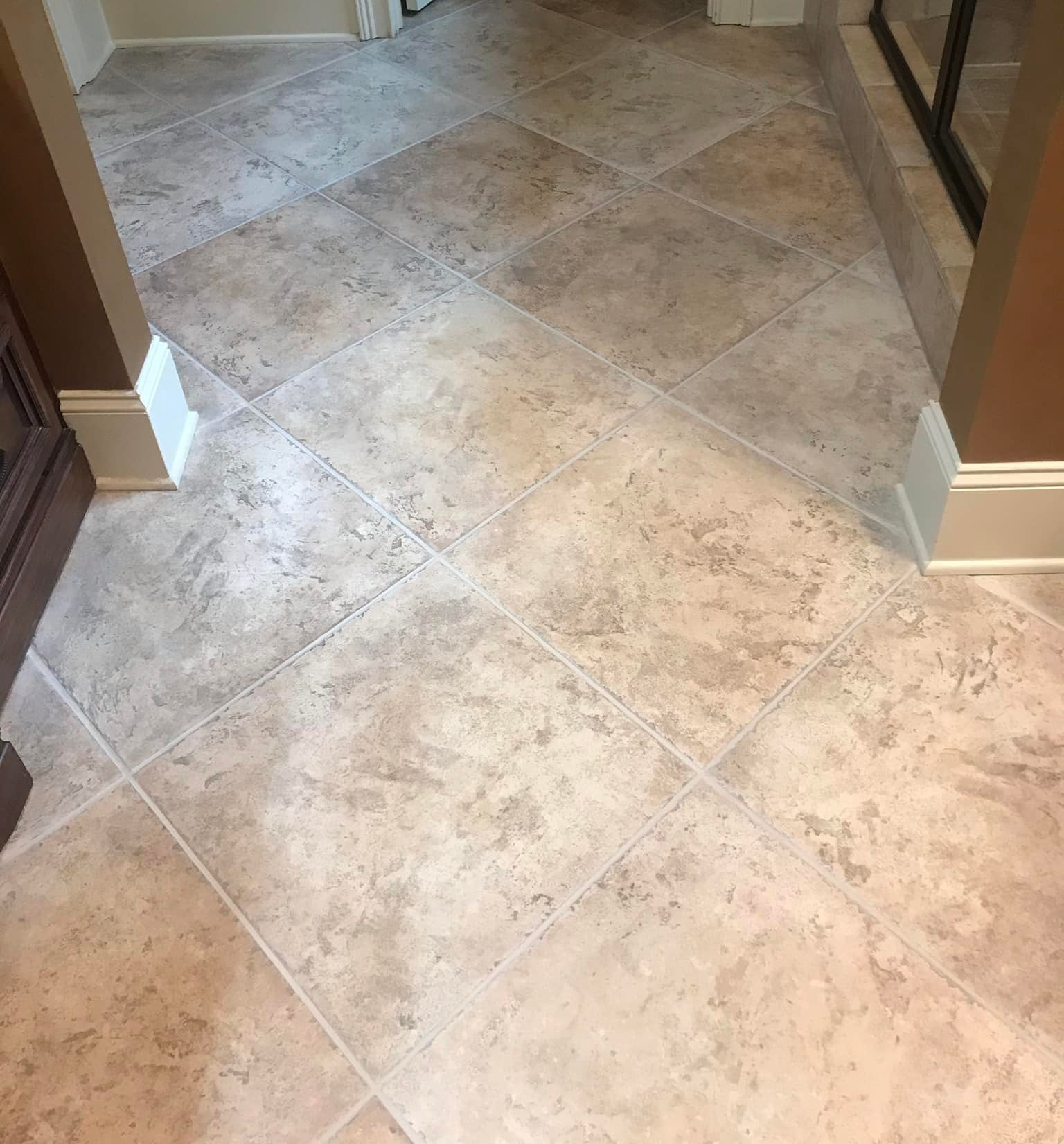 Tan tile flooring in a bathroom. Diagonal pattern with light grout.