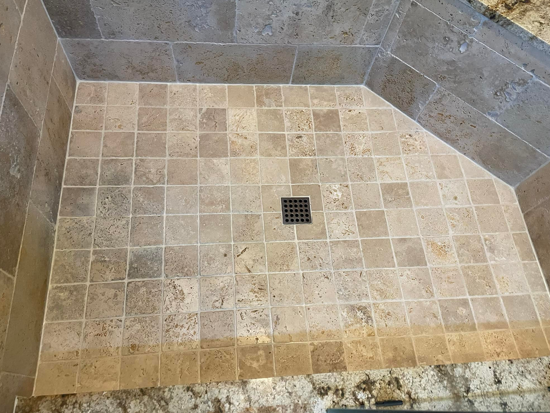 Stone tile shower floor with drain.