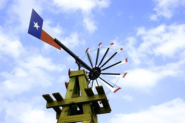 The top of a small windmill decorated with the Texas flag.